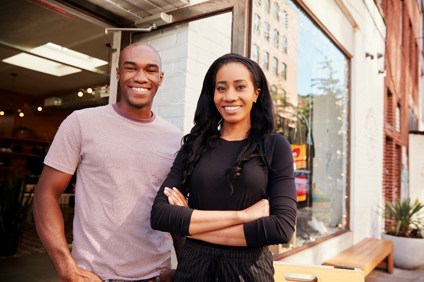 A married African-American couple standing in front of their business.