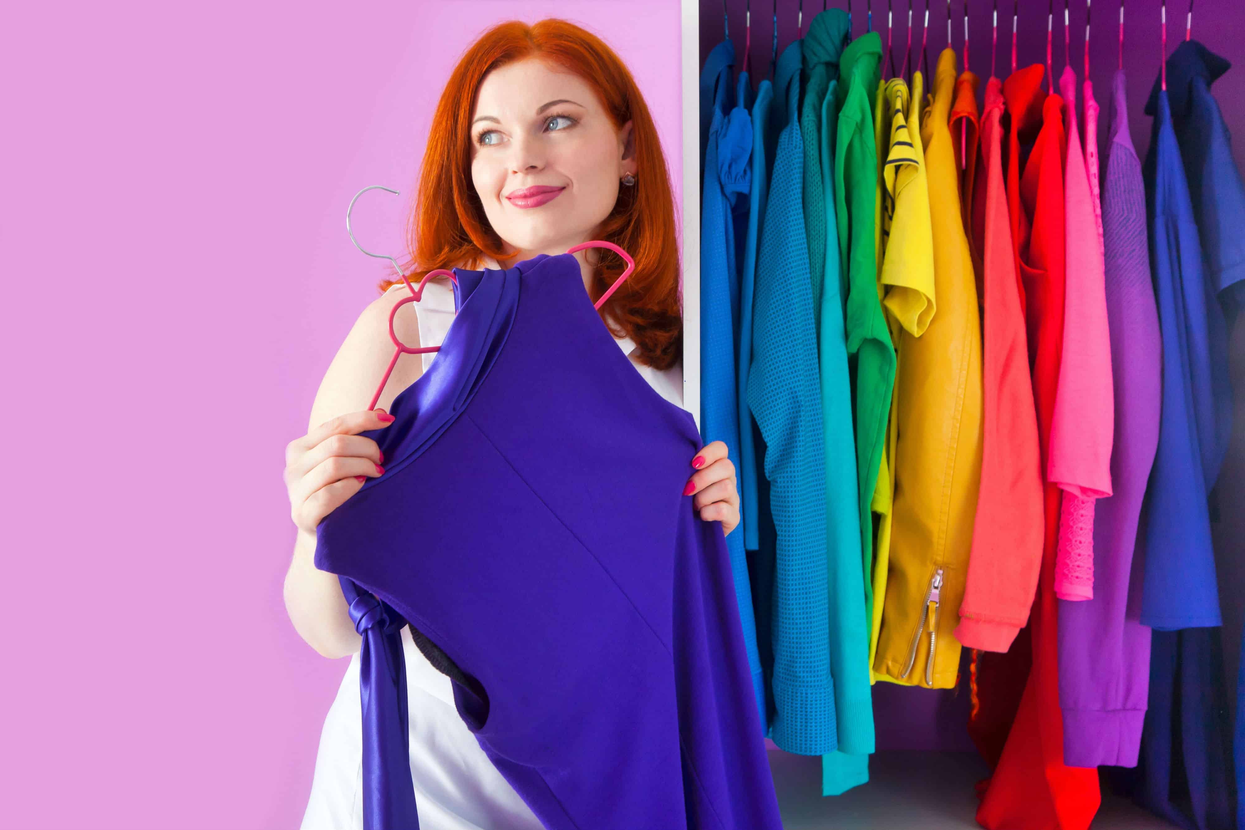 A woman standing in front of a custom closet organized by color.