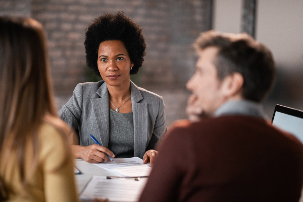 An African American woman discussing franchising options with a couple.